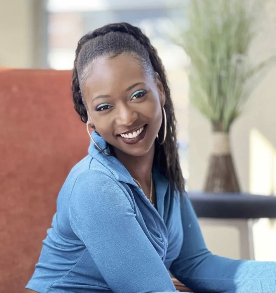 This is a headshot of Dralandra Larkins, a new COMPAS Teaching Artist. She is a young African-American women, probably in her late 20s or early 30s. She is wearing a light blue sweater and smiling at the camera. 